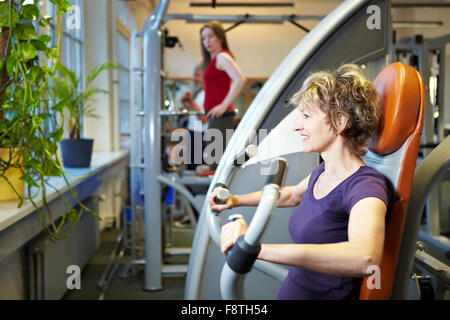 Glückliche Frau am Rudergerät im Fitness-Studio trainieren Stockfoto