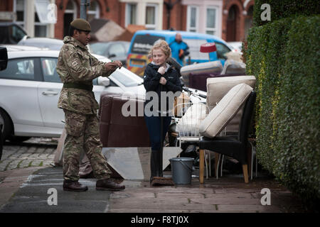 Ein Mitglied der Duke of Lancaster Regiment, mit Sitz in Preston, Lancashire, ein Bewohner von Warwick Road in Carlisle helfen entfernen Sie Möbel und andere Haushalte waren beschädigt durch Hochwasser am vergangenen Wochenende. Rekord Regen fallen in Cumbria verursacht Überschwemmungen auf mehrere Bereiche von Carlisle, wodurch Häuser durch Rettungsdienste evakuiert werden. Stockfoto