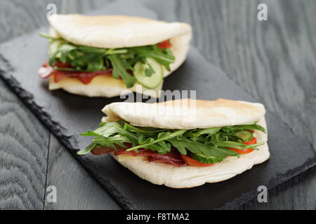 rustikale Sandwiches mit Schinken, Rucola und Tomaten im Fladenbrot Stockfoto