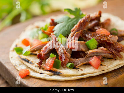 Ein leckeres Schweinefleisch Taco mit Tomaten, Jalapenopfeffer, Frühlingszwiebeln und Koriander auf einem gegrilltem Mais-Tortilla gezogen. Stockfoto