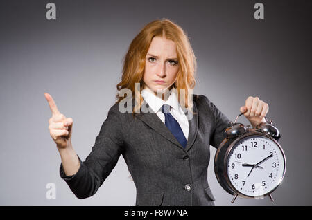Junge schöne Geschäftsfrau mit Wecker zeigt Stockfoto