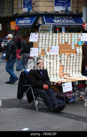 Madrid, Spanien 11. Dezember 2015: Ein Mann sitzt neben seinem Verkaufsstand und verkauft Tickets für die Weihnachtslotterie auf der Plaza Puerta del Sol im Zentrum von Madrid. Die spanische Weihnachtslotterie ist eine der ältesten der Welt und die größte der Welt in Bezug auf die Gesamtauszahlung. Das Siegerticket ist bekannt als „El Gordo“ („der große“ oder „der fette“). Quelle: James Brunker / Alamy Live News Stockfoto