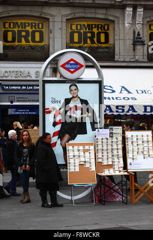 Madrid, Spanien 11. Dezember 2015: Eine Frau verkauft Tickets für die Weihnachtslotterie neben einem Eingang zur U-Bahn-Station Sol an der Plaza Puerta del Sol im Zentrum von Madrid. Die spanische Weihnachtslotterie ist eine der ältesten der Welt und die größte der Welt in Bezug auf die Gesamtauszahlung. Das Siegerticket ist bekannt als „El Gordo“ („der große“ oder „der fette“). Quelle: James Brunker / Alamy Live News Stockfoto
