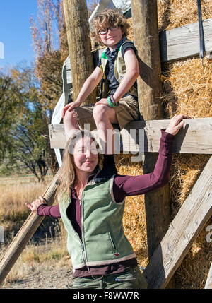 Attraktive Mutter und seinem kleinen Sohn posieren für Fotos von gestapelten Heuballen auf ranch Stockfoto