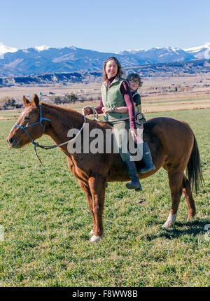 Attraktive Mutter und seinem kleinen Sohn Reiten auf der Ranch Weide Stockfoto