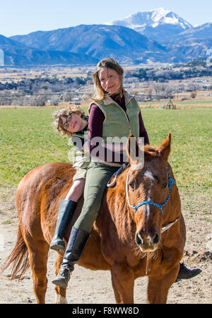 Attraktive Mutter und seinem kleinen Sohn Reiten auf der Ranch Weide Stockfoto