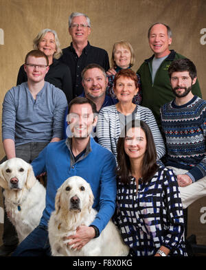 Studio-Porträt der Familie einschließlich der drei Schwestern, Ehepartner & Erwachsene Kinder & zwei Platinum farbige Golden Retriever Hunde Stockfoto