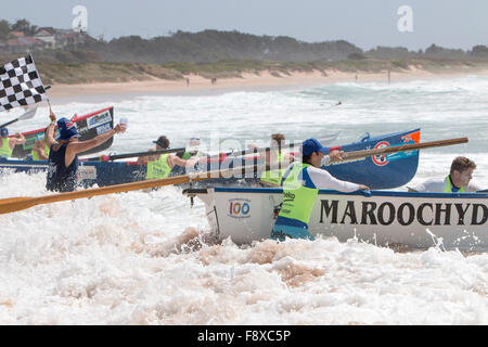 Sydney, Australien. 12. Dezember 2015. Ocean Thunder professioneller Surfbootrennen-Karneval von Dee Why Beach umfasst 24 Elite-Mannschaften für Männer und 12 Elite-Frauen-Teams aus der Gegend um Race Marshall mit karierter Flagge, die sich auf eines der Surfbootrennen vorbereiten Guthaben: model10/Alamy Live News Stockfoto