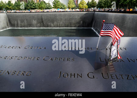 US-Flagge und Fotografie platziert auf den Namen der Opfer des Terroranschlags auf die National 9/11 Memorial, New York City, USA Stockfoto