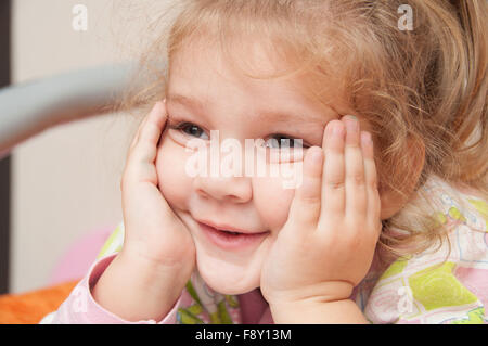 Fröhliches drei Jahre alten Mädchen auf dem Bett liegen und sah auf der linken Seite Stockfoto