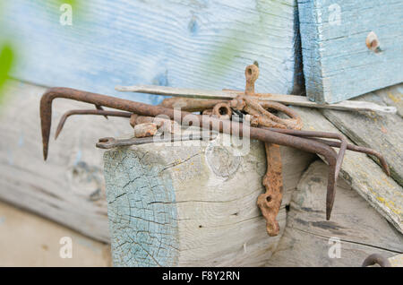 Haufen von alten Werkzeugen und Stück Eisen auf den Holzrahmen des alten Dorfhauses liegend Stockfoto