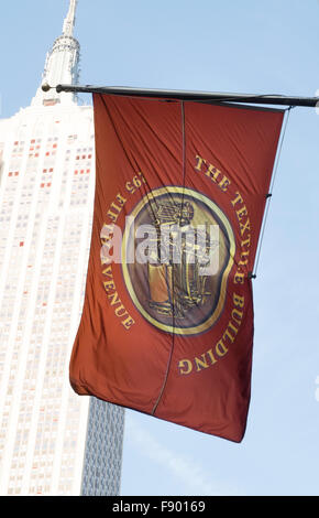 Textile Gebäude Flagge auf der Fifth Avenue mit dem Empire State Building im Hintergrund, NYC Stockfoto