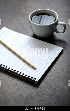 Öffnen Sie ein leeres weißes Notebook, Stift und Tasse Kaffee auf dem Schreibtisch Stockfoto