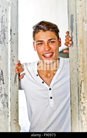 Hübscher lächelnd junger Mann alte Tür lädt Betrachter eingeben Stockfoto