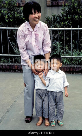 Eine chinesische Mutter stellt stolz ihr ängstlich Zwillingssöhne für einen ausländischen Besucher Kamera auf einem Bürgersteig in Shanghai in der Volksrepublik China (PRC), Ost-Asien. Zwillinge waren eine zulässige Ausnahme Chinas "ein-Kind-Regel", die im Jahr 1978 als Bestandteil einer Politik der Familienplanung begann, die Nation steigenden Bevölkerungswachstum zu kontrollieren. Im Jahr 2015 wurde bekannt, dass zwei Kinder pro Paar in Zukunft erlaubt sein werden. Da Baby-jungen über Mädchen begünstigt sind, gibt es Millionen mehr Männer als Frauen in der Volksrepublik China. Stockfoto