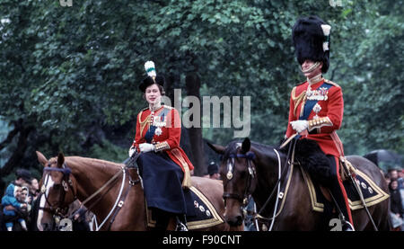 Eine junge Königin Elizabeth II. Und Prinz Philip reiten ihre Pferde vom Buckingham Palace entlang der Straße im Juni 1963 bis zur Trooping the Color Ceremony in London, England. Dieses jährliche britische königliche Ereignis markiert auch den offiziellen Geburtstag der Königin und wird gemeinhin als die Queen's Birthday Parade; sie war 37 Jahre alt zu der Zeit dieses Foto aufgenommen wurde. Seit 1987 reist die Königin in einer Kutsche statt zu Pferd zur Zeremonie. Historisches Foto. Copyright Michele & Tom Grimm. Stockfoto