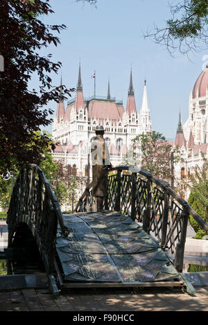 Eine Skulptur von Imre Nagy, ein Mann auf einer kleinen Brücke mit Blick auf das Parlamentsgebäude, Budapest, Ungarn. Stockfoto