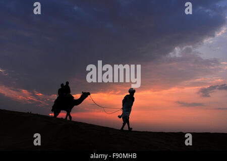 Touristen genießen Kamelritt und Schönheit der Wüste Thar Abend während Jaisalmer Desert Festival, Jaisalmer, Rajasthan, Indien. Stockfoto