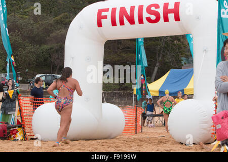 Sydney, Australien. 13. Dezember 2015. Bilgola Beach Schwimmwettlauf über 1,5 km, Teil der jährlichen Pittwater Ocean Swim Series, Sydney, Australien. Bildliche weibliche Schwimmerinnen springen in Richtung Ziellinie Stockfoto