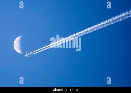 Flugzeug fliegen vorbei an den Mond gegen strahlend blauen Himmel Stockfoto