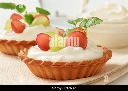 Kleine Creme Törtchen garniert mit frischen Weintrauben Stockfoto