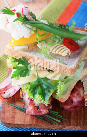 Speck und Käse-Sandwich, garniert mit frischem Gemüse Stockfoto