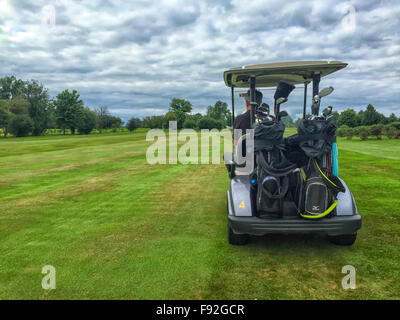 Golfer am Golfplatz in seinem Golfbuggy fahren Stockfoto