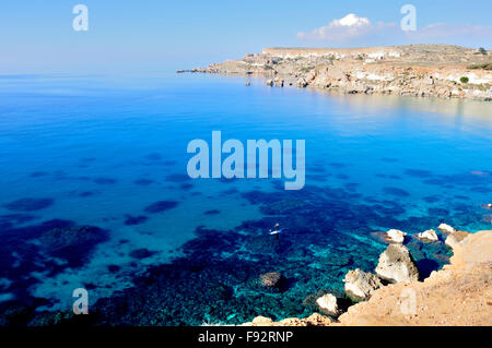 ein strahlend blauen Meer und Himmel in Malta im Dezember. Mann Paddleboarden (kleinen) Stockfoto