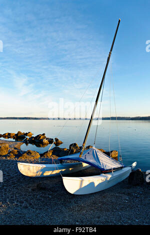 Katamaran Segelboot am Strand in der Nähe von Ufer, See Chiemsee, Chiemgau, Oberbayern, Deutschland, Europa. Stockfoto