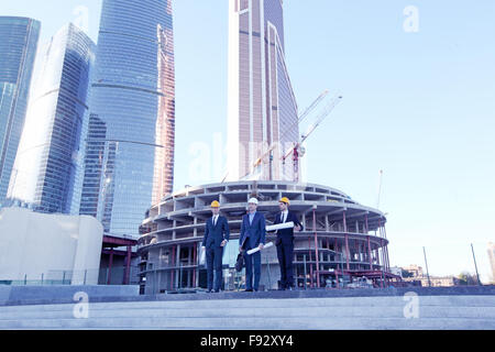 Architekten mit Blaupause an Wolkenkratzern Hintergrund Stockfoto