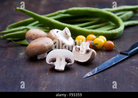Pilze, Tomaten und Stangenbohnen auf einem Holzbrett. Stockfoto