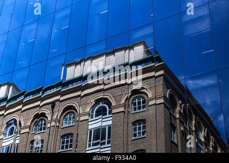 Reflexionen der alten Gebäude und blauer Himmel in die Glasfront eines modernen Bürogebäudes in London, England, Großbritannien Stockfoto