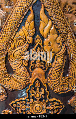 Alte geschnitzte Elefanten und Drachen auf hölzernen Säulen im thailändischen Tempel. Stockfoto