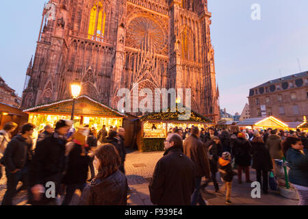 Leute einkaufen bei Ständen vor der Kathedrale von Straßburg am Abend; Straßburg Weihnachtsmarkt in Straßburg Elsass Frankreich Europa Stockfoto