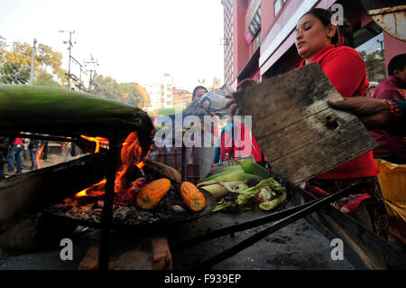 Kathmandu, Nepal. 13. Dezember 2015. Kamala Subedi (blauen Pullover), 38 Jahre und Alisa Khadka (rote Pullover), arbeitet 30 Jahre, ständigen Wohnsitz in Dolkha, als Straßenverkäufer in Kathmandu, geröstetem Mais zu verkaufen. Sie verwendet, um rohe Mais auf NRs. 11 (US$ 0,11) pro Stück zu kaufen und dann verkaufen sie geröstet von 25 (US$ 0,25) pro Stück wo sie NRS 1500 (15 US$) pro Tag zu verdienen. © Narayan Maharjan/Pacific Press/Alamy Live-Nachrichten Stockfoto