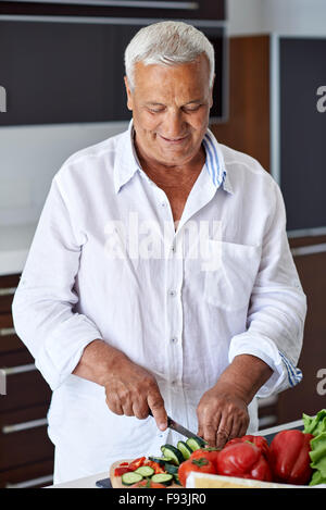 Hübscher senior Mann zu Hause vorbereiten Salat in Küche kochen. Stockfoto