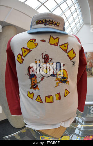 Garden City, New York, USA. 12. Dezember 2015. Ein Vintage Pac-Man-Mania-bunte Baseball-Shirt und Cap aus den 1980er Jahren sind auf dem Display mit andere Arcade-Erinnerungsstücke während Öffnung Tag der Arcade-Alter Ausstellung, wo die Besucher authentische klassische Spiele im Arcade in Long Island im Cradle erleben of Aviation Museum eingerichtet. Auf Hemd spielen Pac-Man-Charaktere Musikinstrumente. Ausstellung läuft vom 12. Dezember 2015 durch 3. April 2016. © Ann Parry/ZUMA Draht/Alamy Live-Nachrichten Stockfoto