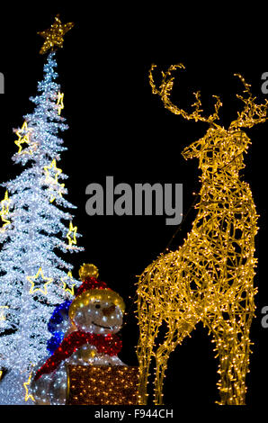 Gelben Hirsch mit Schneemann "und" weißen Weihnachtsbaum Dekoration Lichter vertikal auf schwarzem Hintergrund isoliert Stockfoto