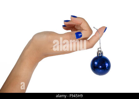 Zarte Frauenhand mit blauen Fingernägeln hält eine blaue Weihnachtskugel auf weißem Hintergrund Stockfoto