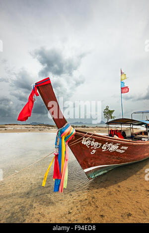 Den traditionellen thailändischen Longtail Boot mit bunten Bändern geschmückt auf dem Bug festgemacht am Klong Muang Beach. Der Provinz Krabi, Thailand. Stockfoto