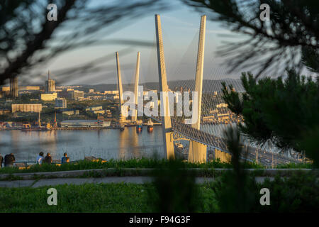 Vladivostok-Brücke bei Sonnenuntergang zwischen Bäumen Stockfoto