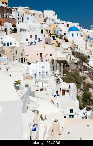 Santorini, Oia. Blick entlang der Stadt mit weiß getünchten, cubiform Häuser auf steilen Klippen erbaut und Griechischen Kirche mit typischen Bavaria Blue Dome. Stockfoto