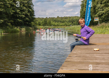 Spychowo, Polen - 23. Juli 2015: Jungen sitzen auf einer Holzbrücke und Angeln. Stockfoto