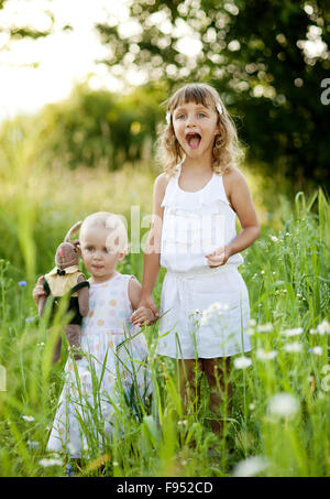 Zwei niedliche kleine Schwestern lachten und spielten in sonnigen, grünen park Stockfoto