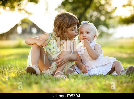 Zwei niedliche kleine Schwestern lachten und spielten in sonnigen, grünen park Stockfoto