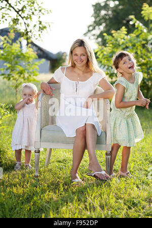 Glückliche junge Mutter verbringt Zeit mit ihren kleinen Töchtern in der grünen Natur. Stockfoto