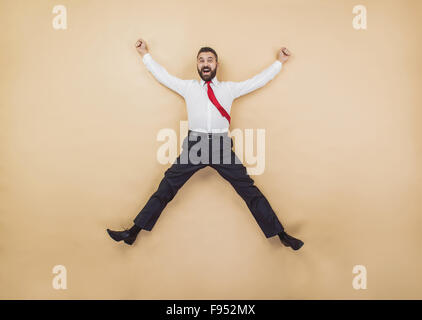 Glücklich-Manager in einer siegreichen Pose hoch springen. Studio auf einem beigen Hintergrund gedreht. Stockfoto