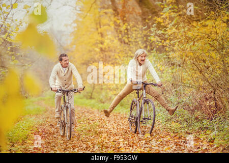 Aktive Senioren mit Fahrrad in der herbstlichen Natur. Sie haben Spaß im Freien. Stockfoto