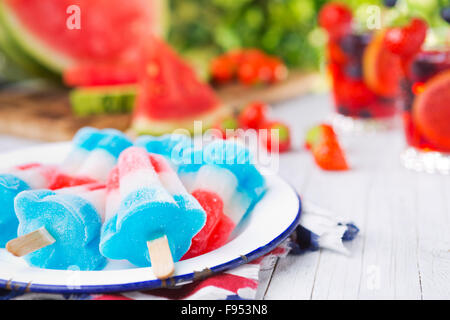 Hausgemachte rot-weiß-blauen Eis am Stiel auf einen Tisch im Freien mit erfrischenden Limonade im Hintergrund. Stockfoto