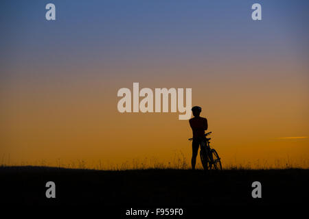 Silhouette der Mountainbiker im Sonnenuntergang auf der Wiese Stockfoto